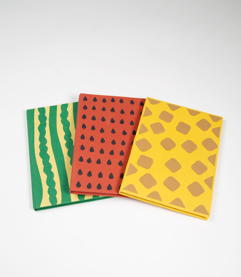 Three patterned notebooks with green, red, and yellow designs on a white background