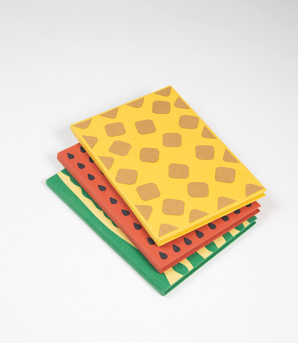 Three patterned notebooks with green, red, and yellow designs on a white background