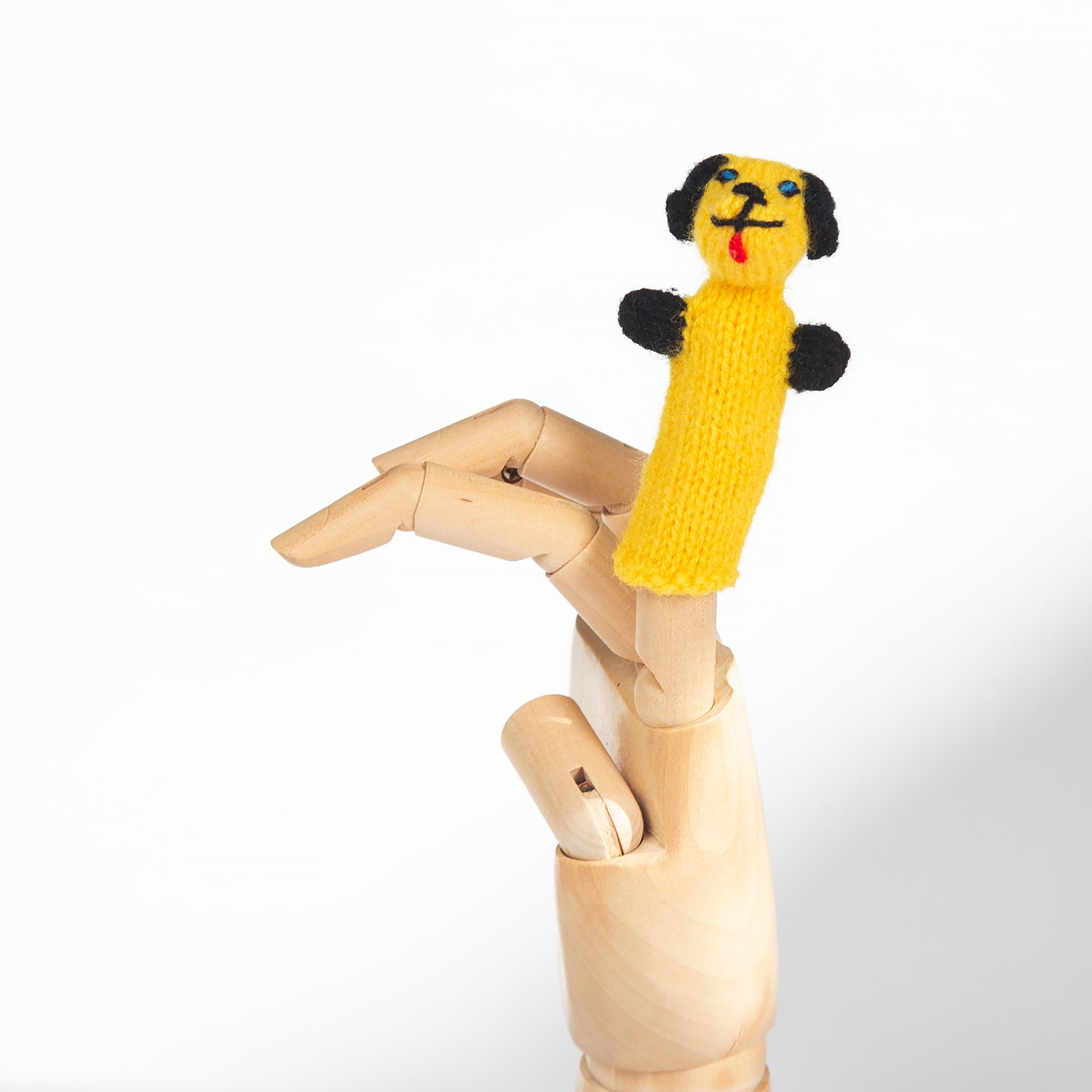 Yellow knitted dog finger puppet on a wooden mannequin arm against a white background