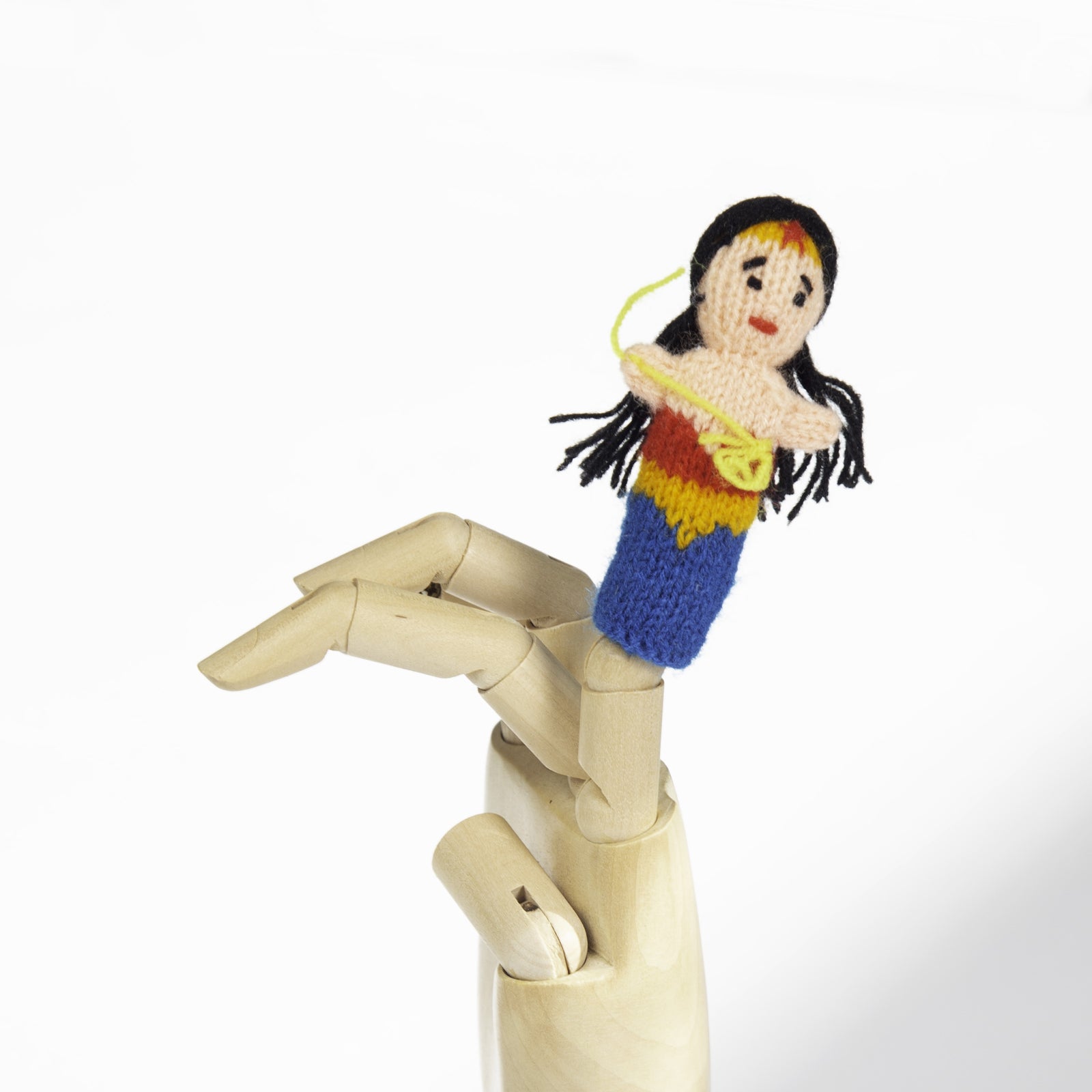 Knitted finger puppet of Wonder Woman with colorful outfit on a wooden mannequin arm against a white background