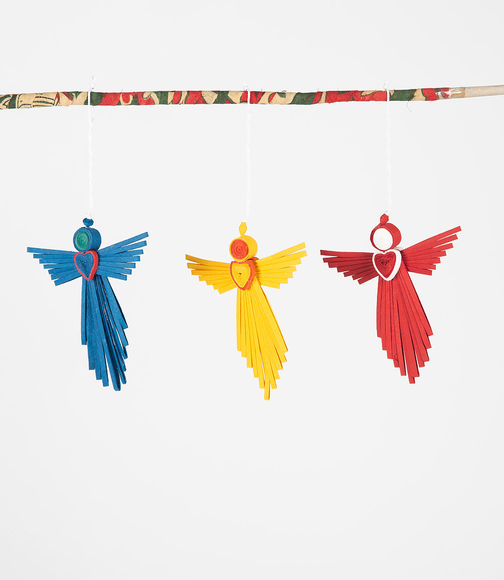 Three colorful angel decorations hanging from a string against a white background