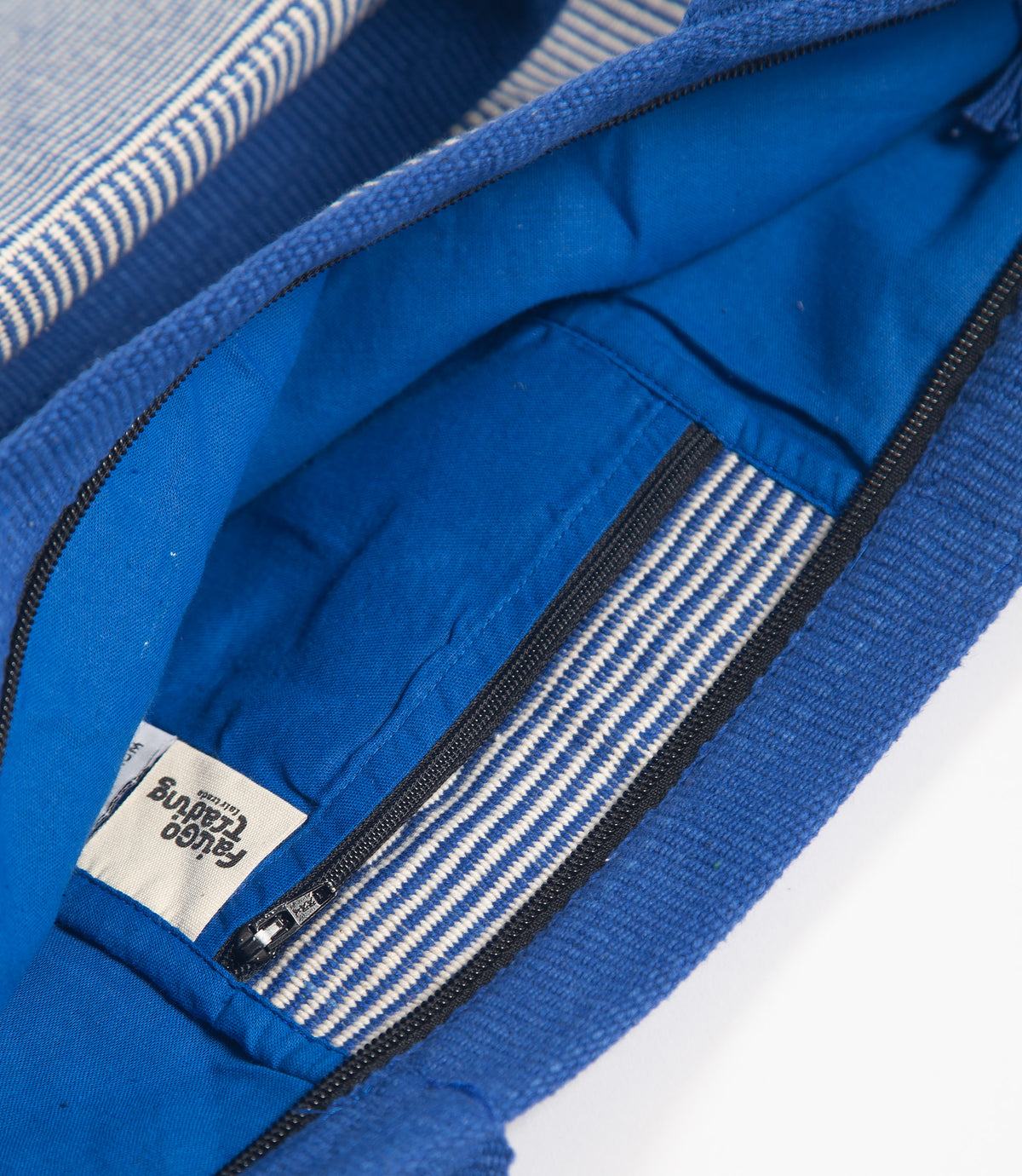 Close-up of a blue bag with striped lining and a brand label.