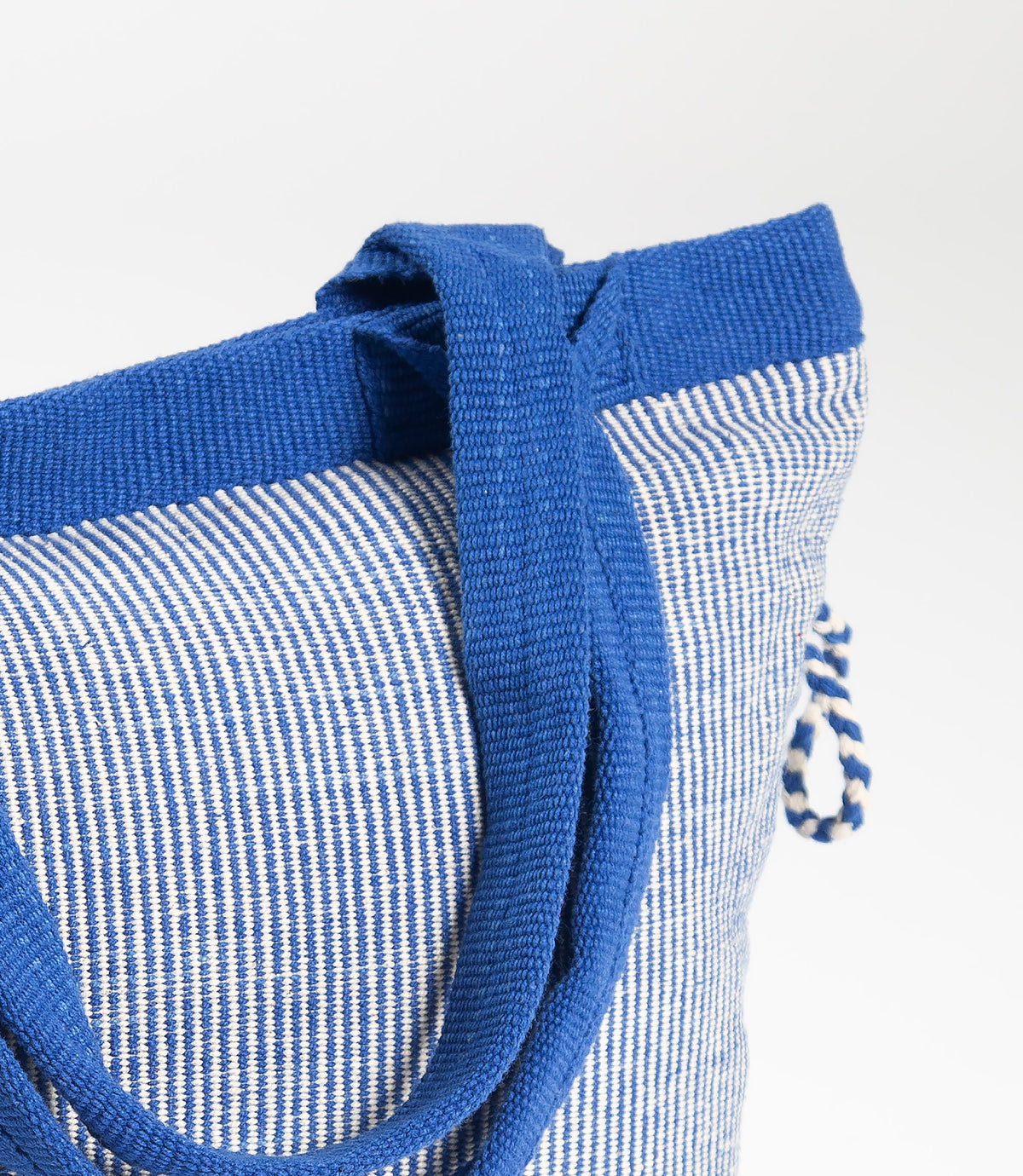Blue and white striped bag with a close-up of the handle on a light gray background