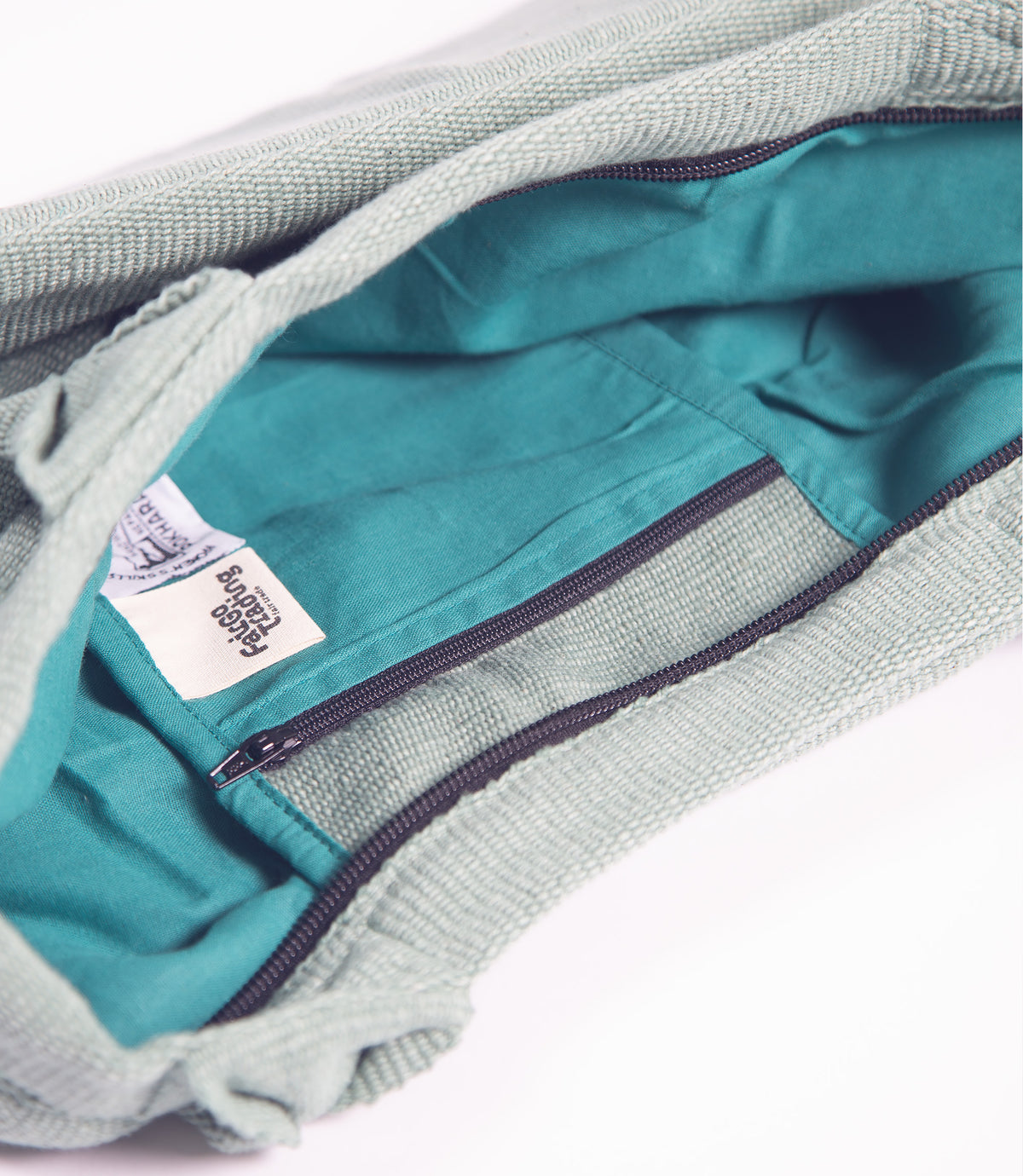 Close-up of a teal garment with a brand label on a white background