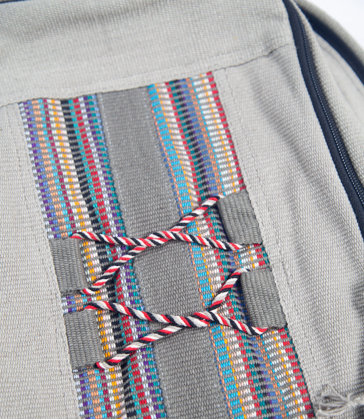 Close-up of a gray bag with colorful woven pattern and red string.