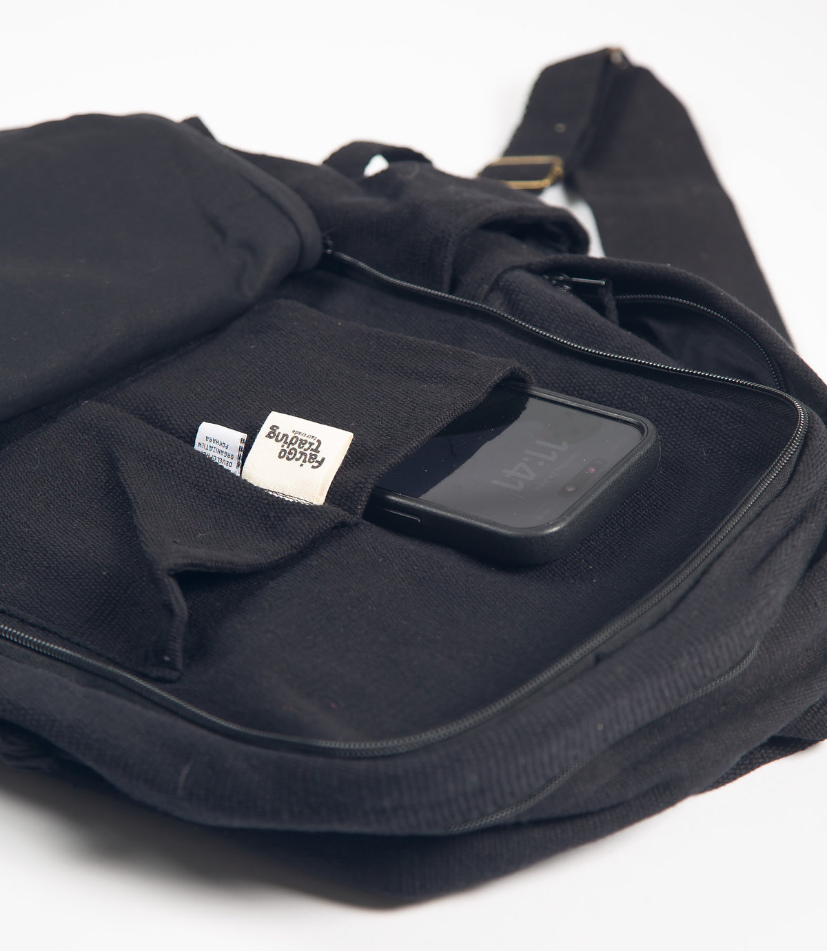 Black backpack with a phone inside a pocket on a white background