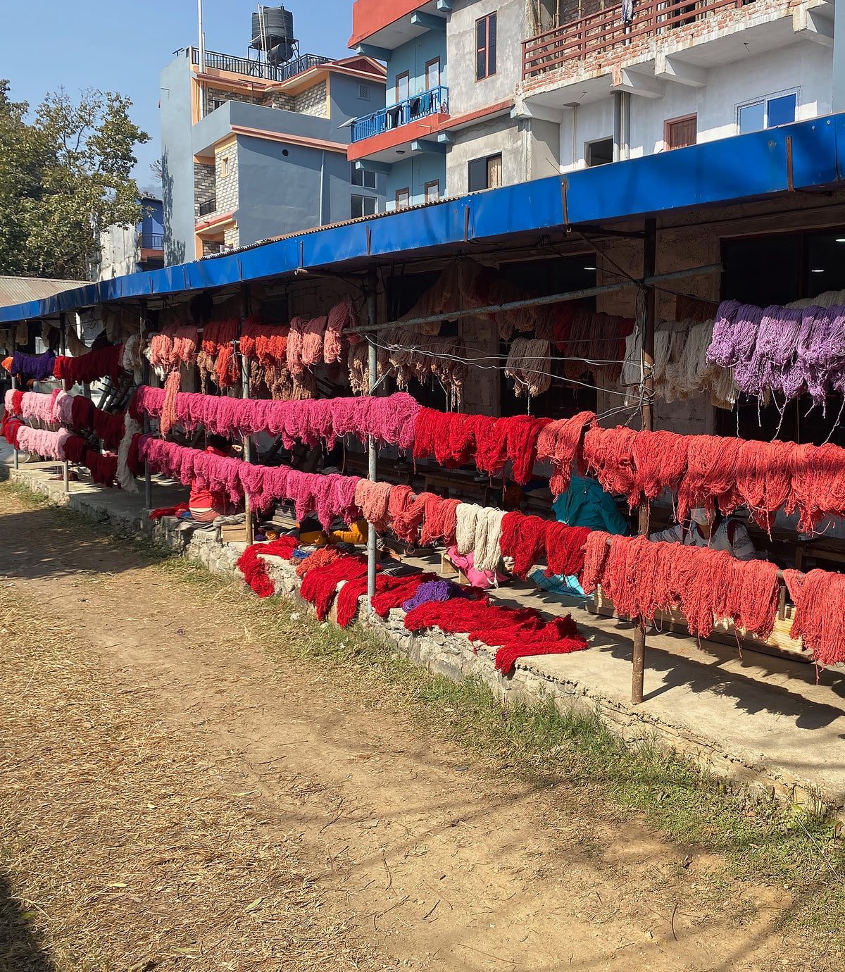 Colorful yarn drying on racks outside a workshop