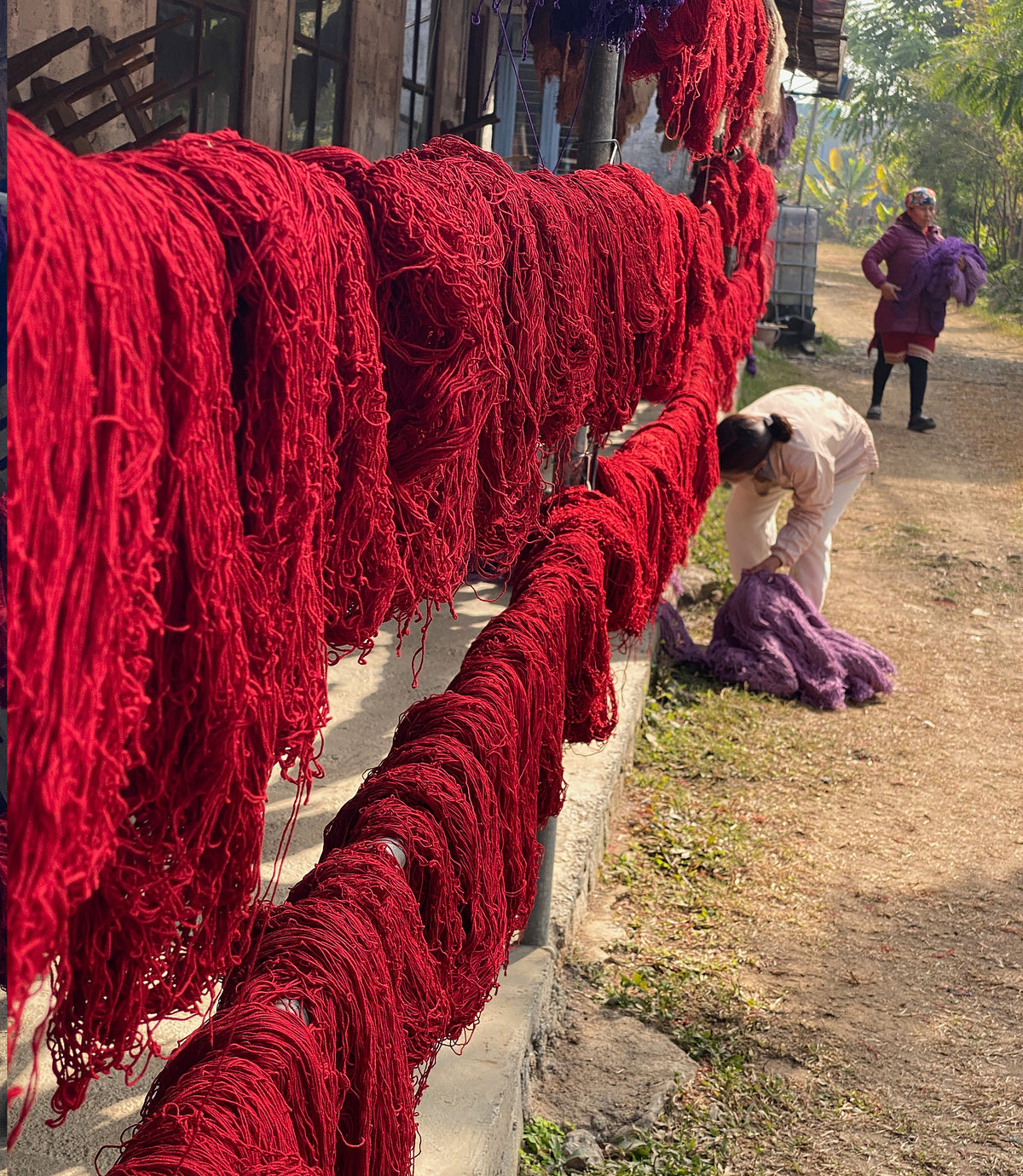 Red yarn hanging outside with producers working nearby
