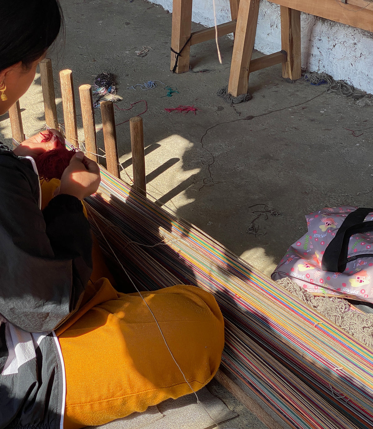 Producer using a loom with colorful fabric.