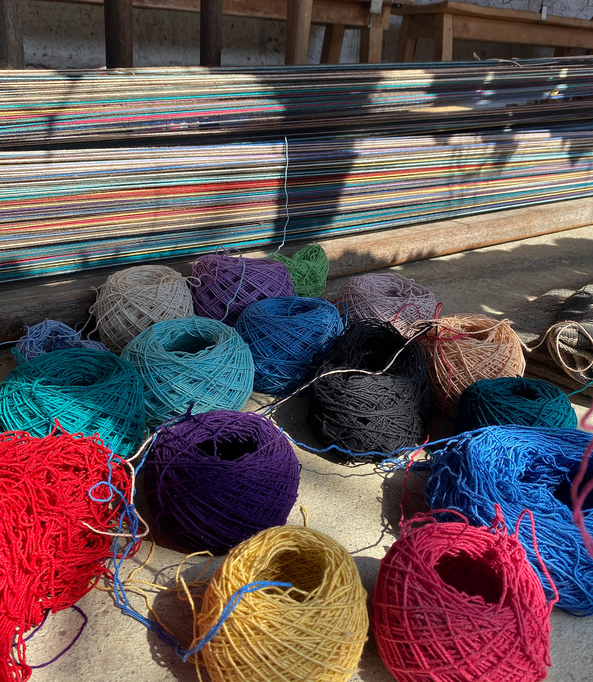 Colorful yarn balls with stripes of fabrics in the background.