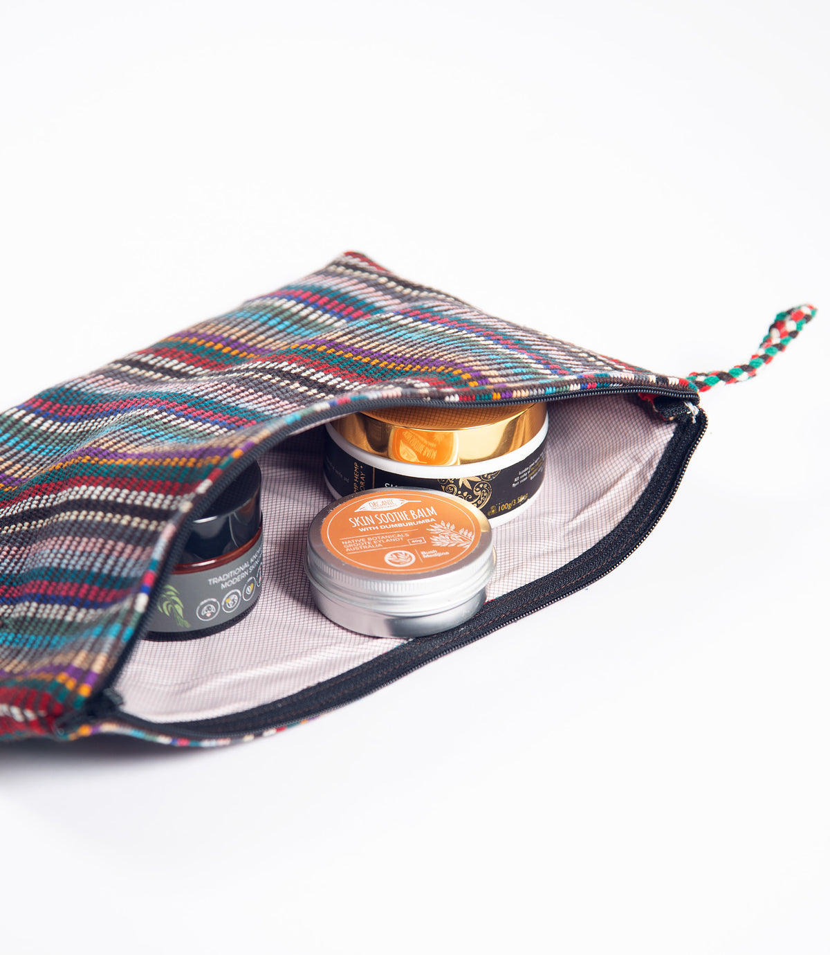 Colorful striped lined pouch with small skincare containers inside on a white background