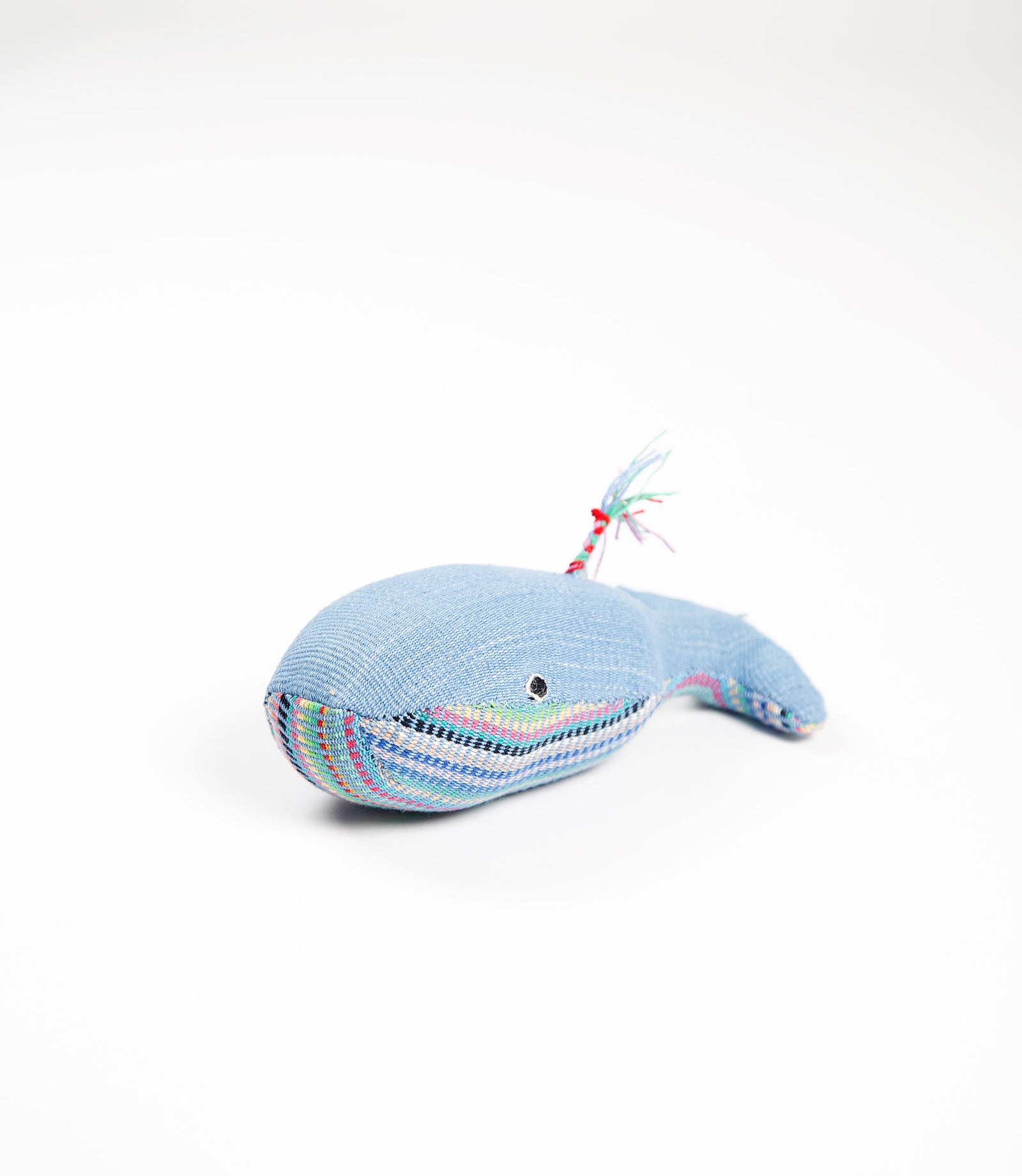 Blue plush whale toy with colorful accents on a white background